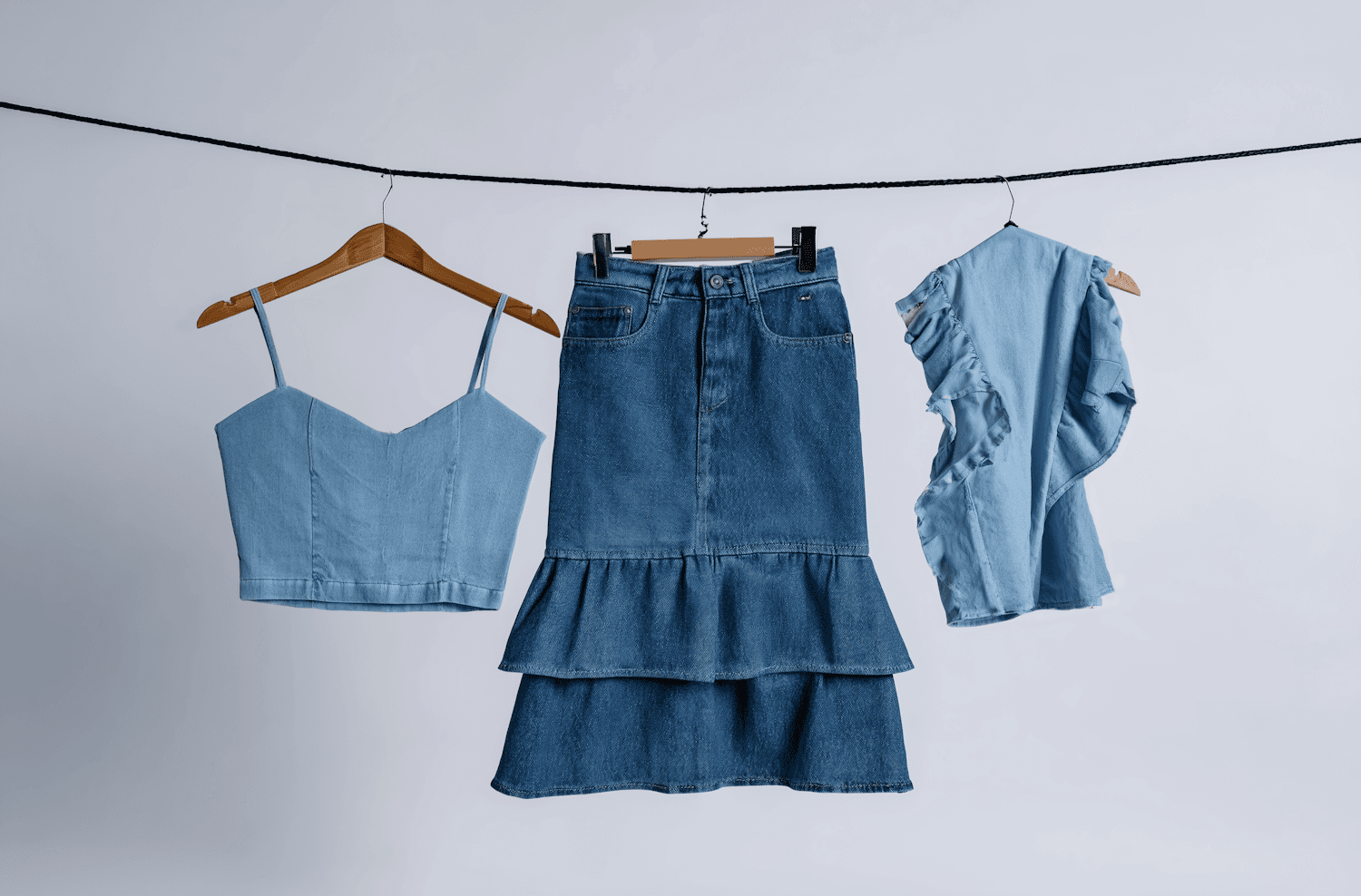 Denim camisole, tiered denim skirt and ruffled chambray top hanging on a line